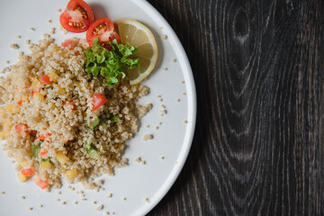 a plate with kenoa salad and vegetables on the background of a wooden table top