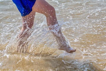 Woman sprinkles sea water with her foot on the beach. Summer and vacation holiday concept.
