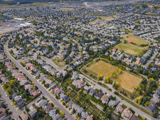 Aerial view of houses and streets in residential neighbourhood during fall season in Calgary,...