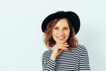 Happy smiling young woman wearing stylish fedora hat and striped shirt