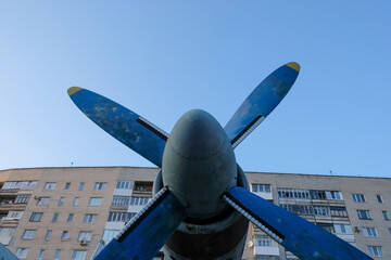 An old aircraft propeller on the background of a tall house and the sky. Copy space.