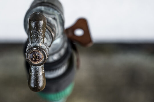 Shallow focus, macro view of the handle of an outside water tap, located outside a farm house. Heavy wear is seen on the handle areas.