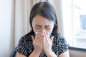 Asian woman sick and sneeze with tissue paper.