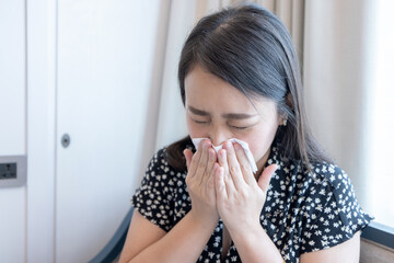 Asian woman sick and sneeze with tissue paper.