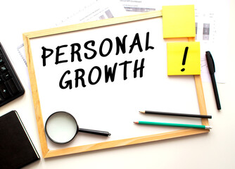 PERSONAL GROWTH text is written on a white office board. Work table with office supplies.