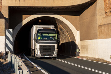 Truck with refrigerated semi-trailer leaving the tunnel of a conventional road, with a two-way...