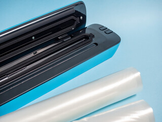 close-up of a blue vacuum packer on a bright blue background. Next to the packaging bags. A machine...