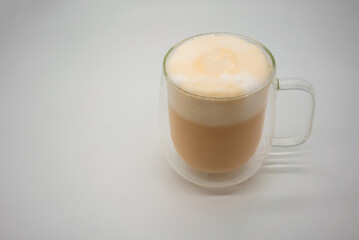 Hot Thai milk tea with milky foam sprinkle with cocoa power for decoration in double wall glass isolated on white