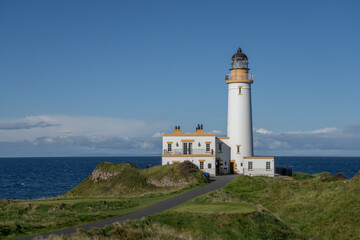 Fototapeta na wymiar Aerial view of Turnberry Lighthouse, Scotland on a sunny day. View looking out to see over the white lighthouse on a blue sky day. 