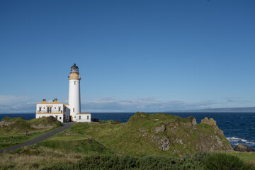 Fototapeta na wymiar Aerial view of Turnberry Lighthouse, Scotland on a sunny day. View looking out to see over the white lighthouse on a blue sky day. 