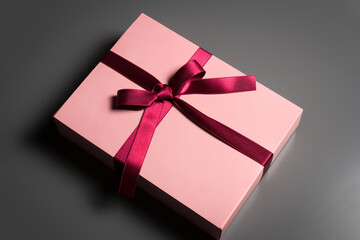 Pink gift box with a red ribon on a dark background.