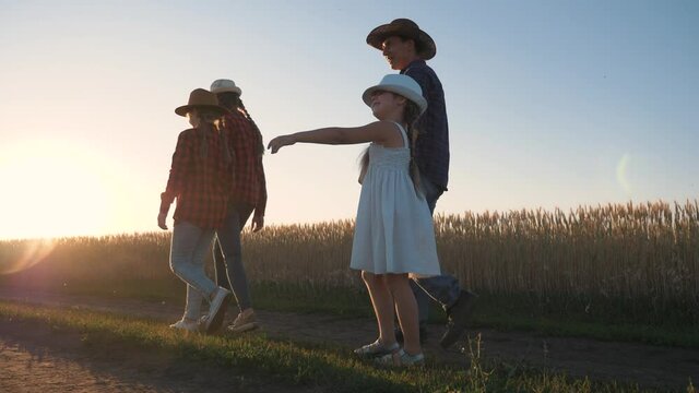 A happy family. Parents and children are walking in the park field in the rays of the sunset. The family is enjoying the countryside. The kids walk with their parents in the wheat field park.