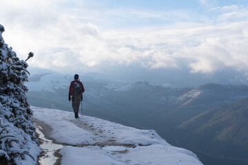 Man walking on a snowy path over a valley