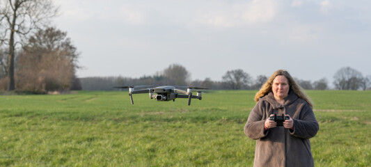 Drohne wird auf einer grünen Wiese von einer Pilotin geflogen