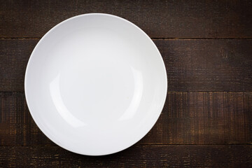 White empty plate wooden background, Top view. Plate made of ceramic. Exquisite tableware.