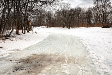 The road is laid on the spring ice of a small frozen forest river