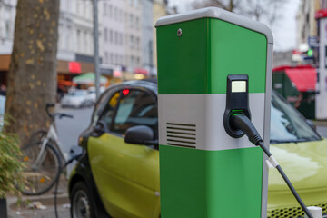 Selective focus, EV Electric Vehicle changing station on sidewalk beside car park on street in Düsseldorf, Germany. 
