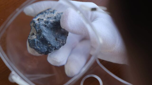 Geologist examines a rock or volcanic sample with a magnifying glass
