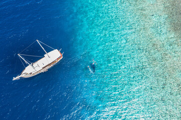 White sailboat, yacht in shallow tropical water. People snorkeling with whale shark. Amazing nature...