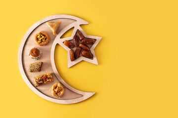 Assortment of Ramadan dessert baklava and dates on yellow background. Copy space