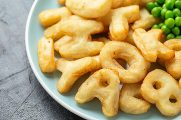 Alphabet potato fries snack with green peas and ketchup on plate. party food © grinchh