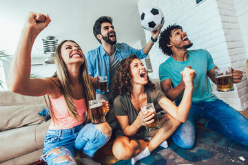 Happy friends or football fans watching soccer on tv and celebrating victory at home.Friendship,...