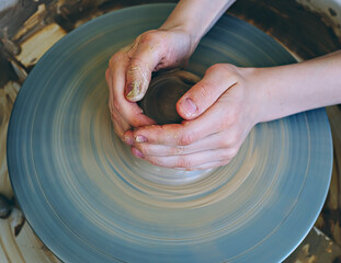 Teenage hands over the potter's wheel. Sculpt from clay in a pottery workshop. Traditional pottery craft. Ceramics workshop concept