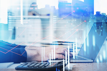 Successful trader is sitting at workplace and typing on laptop