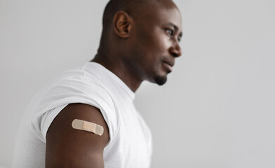 Coronavirus, covid-19 vaccine concept. Black man with an adhesive bandage on shoulder after injection