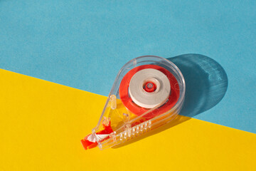 Office tool tape corrector isolated on a yellow and blue background