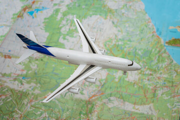 Fototapeta na wymiar A toy plane flies over the geographic map of the world. Airplane travel concept