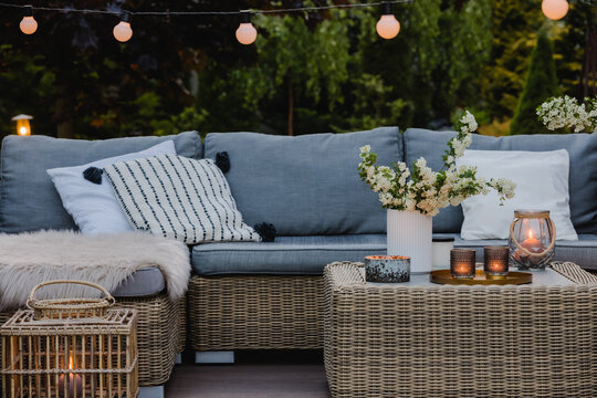 Summer evening on the terrace of beautiful suburban house with patio with wicker furniture and lights