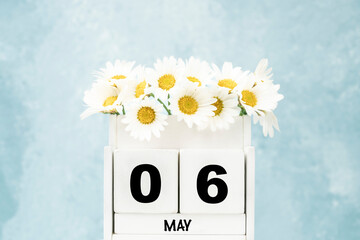 cube calendar for May with daisy flowers over blue with copy space