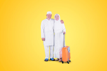 Muslim elderly couple holding a luggage on studio