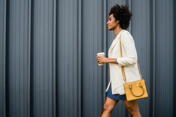 Portrait of afro business woman walking outdoors.