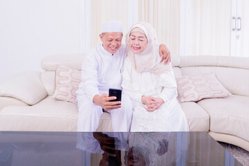 Muslim old couple doing video call with grandchild