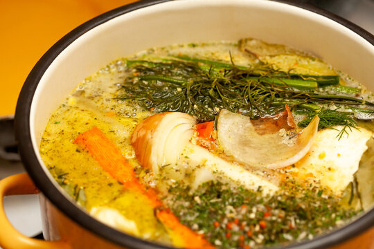 Broth, traditional polish ros&oacute;ł, tasty home made rosol chicken soup cooking in a large pot, surface closeup, detail, dish preparation. Fresh vegetables in meat soup, polish cuisine concept, nobody