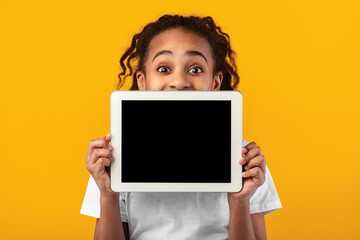 Smiling black girl showing blank tablet screen