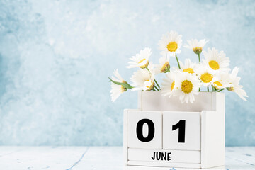 cube calendar for June with daisy flowers over blue