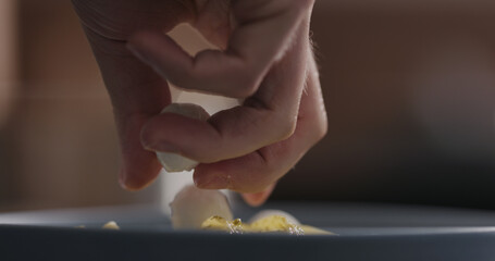 Add mozzarella balls to pesto fettuccine in blue bowl closeup