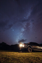 Fototapeta na wymiar Milky way over mountain and couple embracing on pickup at night