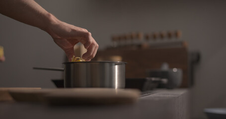 man hand put fettuccine pasta in saucepan with boiling water closeup