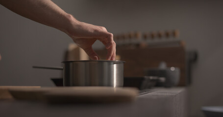 man hand put fettuccine pasta in saucepan with boiling water closeup