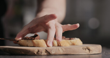 Man spreading chocolate hazelnut spread on baguette slices