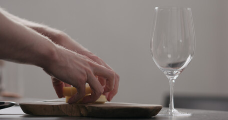 man hands cutting vintage cheese on oliveboard with wine glass