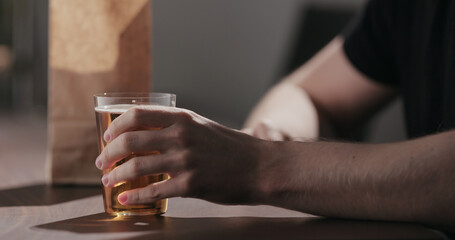 Man drinking amber color fizzy drink with bag of potato chips
