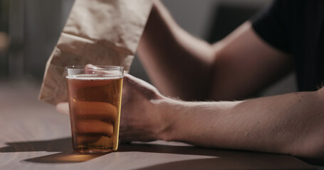 Man drinking amber color fizzy drink with bag of potato chips