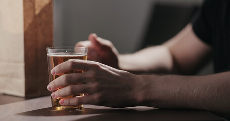 Man drinking amber color fizzy drink with bag of potato chips