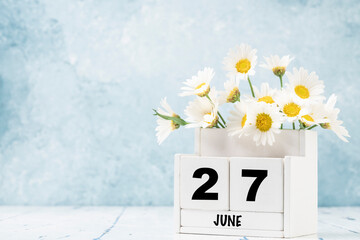 cube calendar for June with daisy flowers over blue