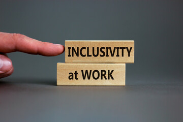 Inclusivity at work symbol. Wooden blocks with words 'Inclusivity at work' on beautiful grey background. Businessman hand. Business, inclusivity at work concept. Copy space.